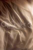 Top view of champagne coloured fabric background, wrinkled natural linen material. Closeup texture of a smooth satin or velvet sheets and luxurious cloth. Abstract dark silk patterns or creases
