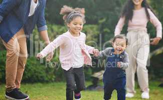 Play is our brains favourite way of learning. two adorable little girls having fun with their family outdoors.