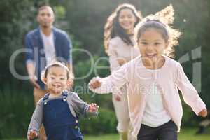 Children are wired for play. Portrait of two adorable little girls having fun with their family outdoors.