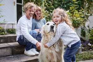 Hes like her big brother. Portrait of a beautiful family playing with their dog while sitting outside together.