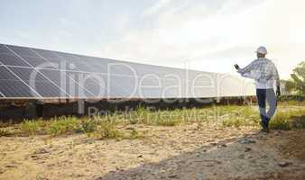 Organically grown veggies always look and taste better. a young man standing next to a solar panel on a farm.