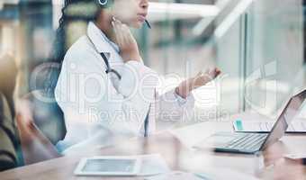 Closeup african american woman doctor using her laptop to do an online remote consult while sitting in her office in the hospital. Testing during the pandemic outbreak. Stop the spread of covid 19