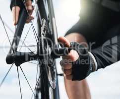 A good cyclist knows his bike. an unrecognizable man checking his tyre while cycling outdoors.