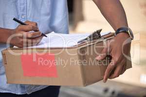 Got to make sure I have the right details. Closeup shot of an unrecognisable delivery man using a clipboard while holding a box.