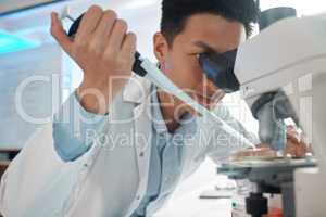 Even the slightest twitch could be a problem. Shot of a male lab tech filling a petri dish underneath a microscope.