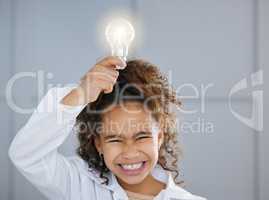 Full of bright ideas. an adorable little girl wearing a labcoat and holding a lightbulb above her head.