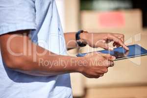 Staying updated throughout his day of deliveries. Closeup shot of an unrecognisable delivery man using a digital tablet while loading boxes from a van.