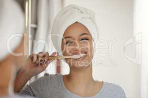 Keeping up with my dental hygiene. a young woman brushing her teeth at home.