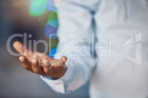 Closeup young african man standing with his hand out holding copyspace while working late at night in his office. African american business man endorsing, recommending or showing a product or advert