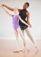 Poetic expressions. a little girl practicing ballet with her teacher in a dance studio.