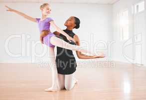 To teach is to pass out peaces of yourself. a little girl practicing ballet with her teacher in a dance studio.