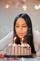 I hope all my wishes come true. a young woman blowing candles on a cake while celebrating her birthday at home.