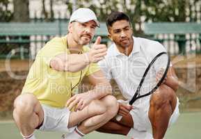 Coming up with a winning strategy. a handsome male coach giving instructions to his younger tennis student on a court.