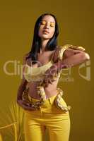 Shes the kinda girl you only dream of. Shot of a fashionable woman holding a snake while modelling a yellow concept.