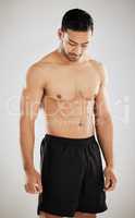 Focus on your gains. Studio shot of a handsome young man showing off his muscular body while posing against a grey background.