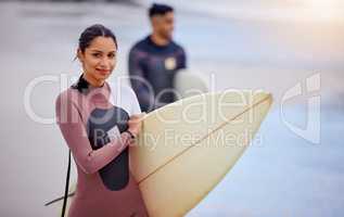 Summers the time for ultimate surfing. Portrait of a young woman surfing at the beach with her boyfriend in the background.