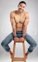 Come on my fitness journey with me. Studio shot of a handsome young man showing off his muscular body while sitting on a chair against a grey background.