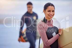 Join me on a surfing adventure. Portrait of a young woman surfing at the beach with her boyfriend in the background.