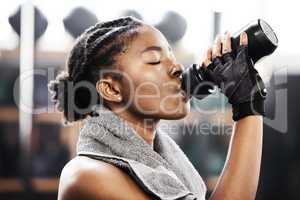 Replacing all that lost sweat. an attractive young woman standing alone in the gym and drinking water after her workout.