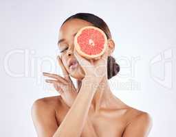 Taking advantage of vitamin Cs best properties. a young woman posing with cut grapefruit against a studio background.