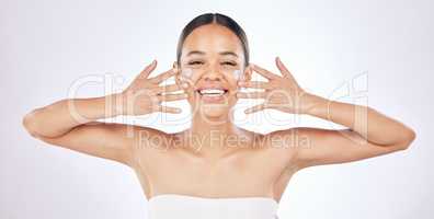 Look at my skin glow. a young woman applying moisturiser to her face against a studio background.