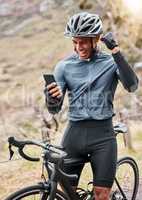 African American cyclist wearing a helmet while using a cellphone and celebrating a win. Male expressing joy while cycling on a bicycle and exercising outside. Success at tracking his speed on an app