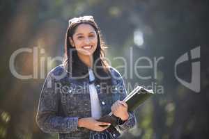 Hopeful and bright-eyed. Portrait of an attractive young female student standing outside on campus.