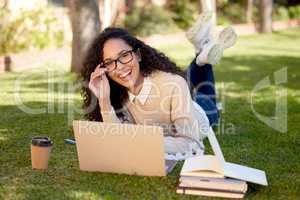 Learning to balance work and pleasure. a beautiful young student using her laptop while relaxing on the grass outside.