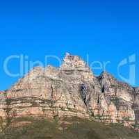 A scenic landscape view of Table Mountain in Cape Town, South Africa against a blue sky background from below. A panoramic view of an iconic landmark and famous travel destination with copyspace