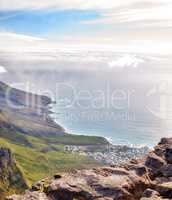 Landscape of Lions Head mountain with houses, ocean and cloudy sky with copy space. Perspective view of green mountains with lots of vegetation overlooking an urban city in Cape Town, South Africa