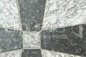 Closeup of black and grey granite tiles on a floor. Creative architecture design of granite tiles cemented together to form a cross pattern. Texture background of natural stone for interior design