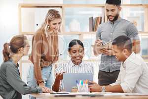 Group of happy diverse colleagues brainstorming together on laptop in an office boardroom. Mixed race businesswoman meeting to explain ideas and strategy to her team in a creative startup agency