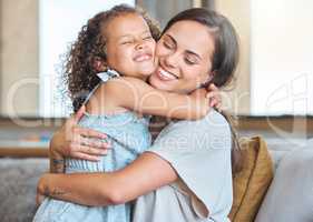 Loving mother and daughter embracing each other sharing hug while sitting on the couch at home. Affectionate parent and child sharing tender moment and home expressing love