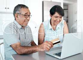 No more long lines for us. a senior couple using a laptop and credit card at home.