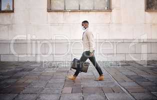 Black businessman travelling alone.A african american businessman walking around town with his luggage while wearing mask to protect himself from the corona virus in the city