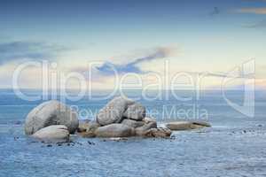 Copyspace at sea with a cloudy blue sky background and rocky coast in Western Cape South Africa. View of calm scenic sea landscape with rocks. Stunning destination for a summer holiday background