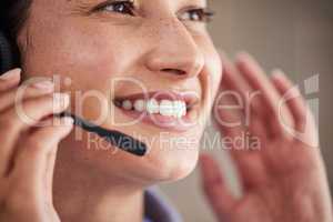 Closeup of young mixed race female call center agent wearing headset and talking to clients customers. Face of smiling and friendly customer service operator answering calls