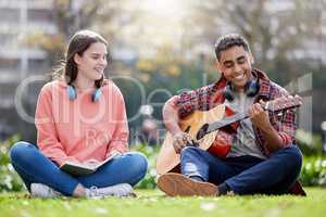This one goes out to my love. a young man and woman playing the guitar on a study break at college.