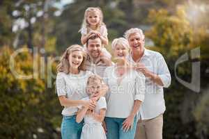 Portrait of a smiling multi generation caucasian family standing close together in the garden at home. Happy adorable girls bonding with their mother, father, grandfather and grandmother in a backyar