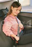 Safety first. a young woman fastening her seatbelt in a car.