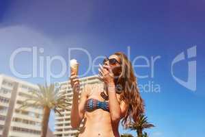 Its a great day for a creamy cone. Shot of a beautiful young woman enjoying an ice cream cone.