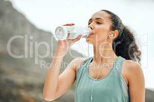 Taking a break to re hydrate. a young woman taking a break from working out to drink water.