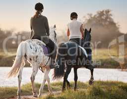 Exploring new paths. two young women out horseback riding together.