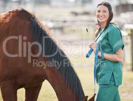 Consider me the horse whisperer. an attractive young veterinarian standing alone and attending to a horse on a farm.