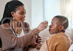 This will make you feel better. a young mother giving her sick son cough syrup at home.