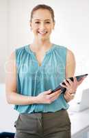 Lets get business underway. an attractive young businesswoman standing alone in the office and holding a digital tablet.