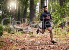 Athletic man running in a park. Muscular male training outside. Jogger starting his morning with some cardio exercises. Sporty mixed race athlete keeping fit in a forest while training for a marathon