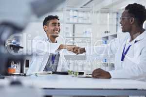 Two diverse mixed race professional scientist fist bumping and smiling while wearing lab coats. Two doctors making an agreement and congratulating one another. Hand gesture greeting of two people