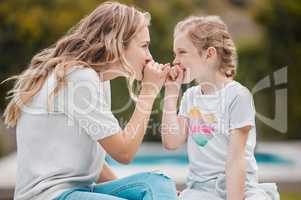 Beautiful young woman and her adorable little girl playing while sitting outside. Blonde mom bonding with her cure daughter outdoors. Family and relationship are a source of love and happiness