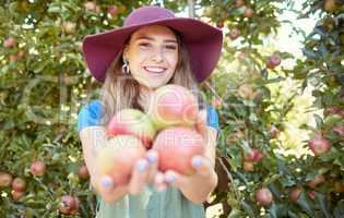 Portrait of one happy young woman holding freshly picked red from trees on sustainable orchard farmland outside on sunny day. Farmer harvesting juicy nutritious organic fruit in season ready to eat